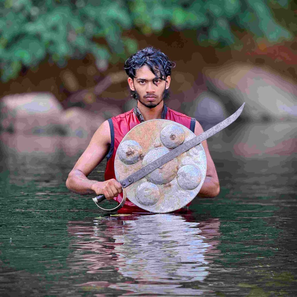 Kalaripayattu practitioner holding traditional sword and shield standing in a river in Wayanad